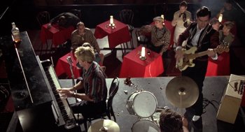 Movie still from “Great Balls of Fire!” (1989), directed by Jim McBride – A group of people sitting at tables playing musical instruments; Wide shot, High angle