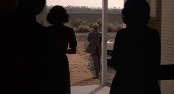 Movie still from “Great Balls of Fire!” (1989), directed by Jim McBride – A man in a gray suit is standing in front of a window; Wide shot, Over the shoulder angle