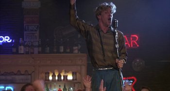 Movie still from “Great Balls of Fire!” (1989), directed by Jim McBride – A man holding a microphone up to his mouth; Medium shot, Low angle