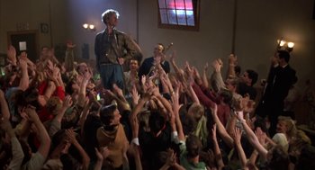 Movie still from “Great Balls of Fire!” (1989), directed by Jim McBride – A crowd of people with their hands up in the air at an event; Wide shot, High angle