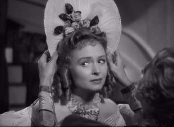 Movie still from “Green Dolphin Street” (1947), directed by Victor Saville – A black and white photo of a woman with a bunch of dolls on her head; Close Up shot, Over the shoulder angle