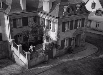 Movie still from “Green Dolphin Street” (1947), directed by Victor Saville – An aerial view of an old house with a man sitting on the porch; Extreme Wide shot, Overhead angle