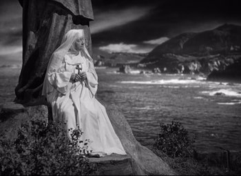 Movie still from “Green Dolphin Street” (1947), directed by Victor Saville – A nun sitting on a rock near the water; Wide shot, Low angle
