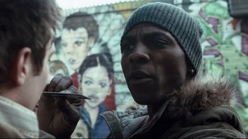 Movie still from “Green Street Hooligans” (2005), directed by Lexi Alexander – A man holding a paintbrush in front of a mural; Close Up shot, Over the shoulder angle
