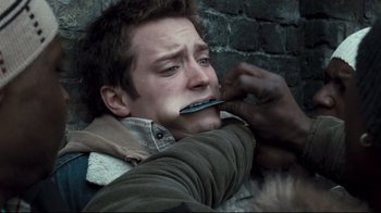 Movie still from “Green Street Hooligans” (2005), directed by Lexi Alexander – A man with a knife in his mouth is laying on the ground; Close Up shot, Over the shoulder angle