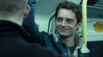 Movie still from “Green Street Hooligans” (2005), directed by Lexi Alexander – A young man is smiling while sitting on a bus; Close Up shot, Over the shoulder angle