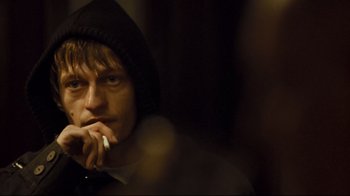 Movie still from “Green Street Hooligans” (2005), directed by Lexi Alexander – A man in a hooded jacket is holding a cell phone to his ear; Close Up shot, Over the shoulder angle