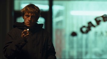 Movie still from “Green Street Hooligans” (2005), directed by Lexi Alexander – A young man is looking at his cell phone; Medium shot, Low angle