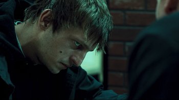 Movie still from “Green Street Hooligans” (2005), directed by Lexi Alexander – A young man with blue eyes looking down; Close Up shot, Over the shoulder angle