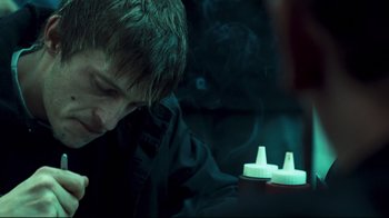 Movie still from “Green Street Hooligans” (2005), directed by Lexi Alexander – A man sitting in front of a lit up bottle; Close Up shot, Over the shoulder angle