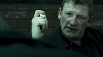 Movie still from “Green Street Hooligans” (2005), directed by Lexi Alexander – A person holding a cigarette in his hand; Close Up shot, Over the shoulder angle