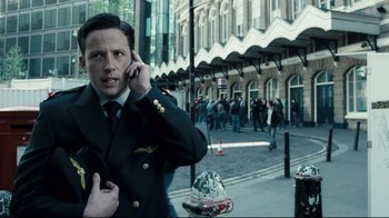 Movie still from “Green Street Hooligans” (2005), directed by Lexi Alexander – A man talking on a cell phone while standing on a sidewalk; Close Up shot, Low angle