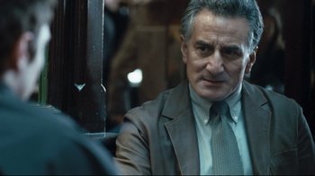 Movie still from “Green Street Hooligans” (2005), directed by Lexi Alexander – A man in a suit and tie sitting in front of a window; Close Up shot, Over the shoulder angle