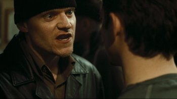 Movie still from “Green Street Hooligans” (2005), directed by Lexi Alexander – A man in a black hat is talking to another man in a black jacket; Close Up shot, Over the shoulder angle