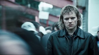 Movie still from “Green Street Hooligans” (2005), directed by Lexi Alexander – A young man standing in front of a group of people; Close Up shot, Over the shoulder angle
