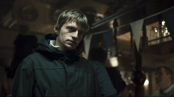 Movie still from “Green Street Hooligans” (2005), directed by Lexi Alexander – A man in a black jacket standing in a room; Close Up shot, Over the shoulder angle