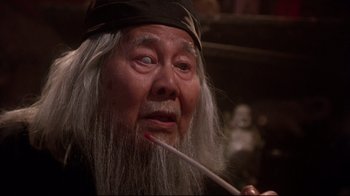 Movie still from “Gremlins 2: The New Batch” (1990), directed by Joe Dante – An old man with long white hair is holding a pipe; Close Up shot, Low angle