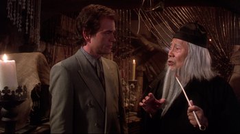 Movie still from “Gremlins 2: The New Batch” (1990), directed by Joe Dante – A man in a suit talking to an older man; Medium shot, Over the shoulder angle