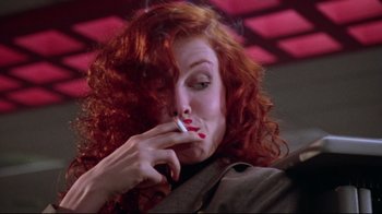 Movie still from “Gremlins 2: The New Batch” (1990), directed by Joe Dante – A woman with red curly hair is smoking a cigarette; Close Up shot, Low angle
