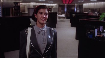 Movie still from “Gremlins 2: The New Batch” (1990), directed by Joe Dante – A woman standing in an office wearing a suit and tie; Medium shot, Low angle