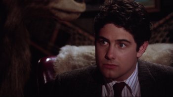 Movie still from “Gremlins 2: The New Batch” (1990), directed by Joe Dante – A man in a suit sitting in a chair; Close Up shot, Over the shoulder angle