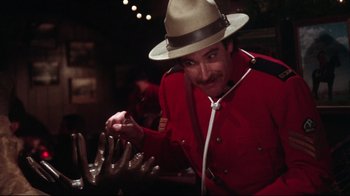 Movie still from “Gremlins 2: The New Batch” (1990), directed by Joe Dante – A man in a red jacket and a hat; Medium shot, Over the shoulder angle