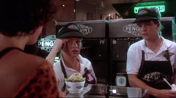 Movie still from “Gremlins 2: The New Batch” (1990), directed by Joe Dante – A woman holding a bowl of ice cream in her hand; Medium shot, Over the shoulder angle