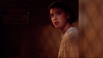 Movie still from “Gremlins 2: The New Batch” (1990), directed by Joe Dante – A young woman standing in a dimly - lit room; Close Up shot, Low angle