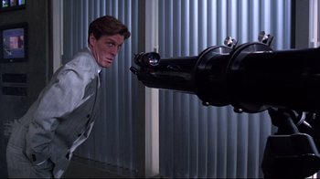 Movie still from “Gremlins 2: The New Batch” (1990), directed by Joe Dante – A man in a suit and tie looking at a telescope; Medium shot, Low angle