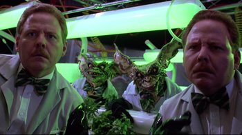 Movie still from “Gremlins 2: The New Batch” (1990), directed by Joe Dante – Two men dressed in green and white are posing for a picture; Medium shot, Low angle