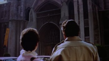 Movie still from “Gremlins 2: The New Batch” (1990), directed by Joe Dante – Two people are standing in front of an old church; Wide shot, Low angle