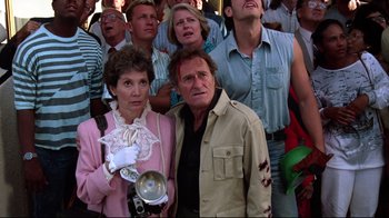 Movie still from “Gremlins 2: The New Batch” (1990), directed by Joe Dante – A man and a woman standing next to each other in front of a crowd; Medium shot, Low angle