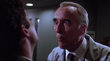 Movie still from “Gremlins 2: The New Batch” (1990), directed by Joe Dante – An older man in a suit and tie talking to a younger man; Close Up shot, Low angle