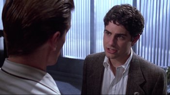 Movie still from “Gremlins 2: The New Batch” (1990), directed by Joe Dante – A man in a brown jacket talking to another man in a white dress shirt; Close Up shot, Over the shoulder angle