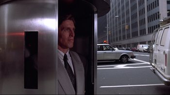 Movie still from “Gremlins 2: The New Batch” (1990), directed by Joe Dante – A man wearing a suit and tie in an elevator; Medium shot, Low angle