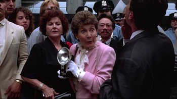 Movie still from “Gremlins 2: The New Batch” (1990), directed by Joe Dante – An older woman in a pink jacket holding a silver spoon; Close Up shot, Low angle