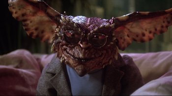 Movie still from “Gremlins 2: The New Batch” (1990), directed by Joe Dante – A person wearing glasses and a jacket; Close Up shot, High angle