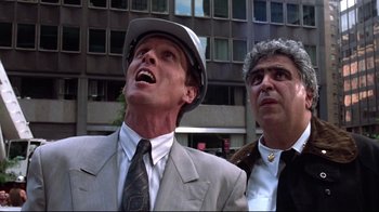 Movie still from “Gremlins 2: The New Batch” (1990), directed by Joe Dante – A man in a suit and a man in a hat looking up; Close Up shot, Low angle