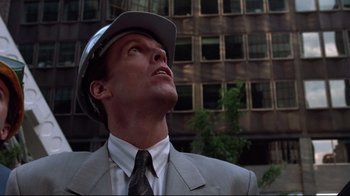 Movie still from “Gremlins 2: The New Batch” (1990), directed by Joe Dante – A man in a suit and hat looking up at a building; Close Up shot, Low angle
