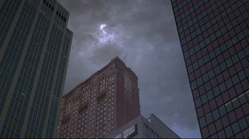 Movie still from “Gremlins 2: The New Batch” (1990), directed by Joe Dante – A building is seen against a cloudy sky in a city; Extreme Wide shot, Low angle
