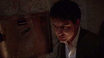 Movie still from “Gremlins 2: The New Batch” (1990), directed by Joe Dante – A man in a dark room looking at the camera; Close Up shot, Low angle