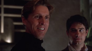 Movie still from “Gremlins 2: The New Batch” (1990), directed by Joe Dante – A person smiling with another person in the background; Close Up shot, Low angle