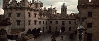 Movie still from “Greystoke: The Legend of Tarzan, Lord of the Apes” (1984), directed by Hugh Hudson – A courtyard with horses and carriages in front of a castle; Extreme Wide shot, High angle