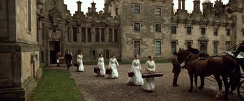 Movie still from “Greystoke: The Legend of Tarzan, Lord of the Apes” (1984), directed by Hugh Hudson – A group of women walking down a street holding suitcases; Extreme Wide shot, Low angle