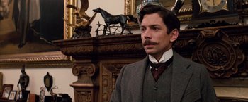 Movie still from “Greystoke: The Legend of Tarzan, Lord of the Apes” (1984), directed by Hugh Hudson – A man standing in front of a fireplace with a horse on the mantel; Close Up shot, Low angle