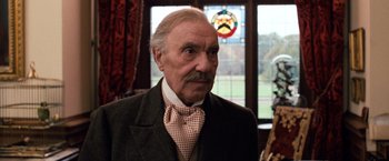 Movie still from “Greystoke: The Legend of Tarzan, Lord of the Apes” (1984), directed by Hugh Hudson – An older man with a mustache wearing a suit; Close Up shot, Low angle