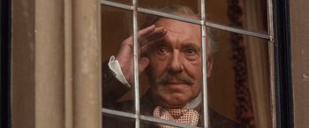 Movie still from “Greystoke: The Legend of Tarzan, Lord of the Apes” (1984), directed by Hugh Hudson – An old man with a mustache is looking through the bars of a window; Close Up shot, Low angle