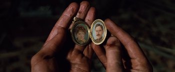 Movie still from “Greystoke: The Legend of Tarzan, Lord of the Apes” (1984), directed by Hugh Hudson – A man holding a picture of a man and a woman in an open case; Extreme Close Up shot, Overhead angle