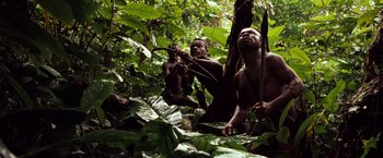 Movie still from “Greystoke: The Legend of Tarzan, Lord of the Apes” (1984), directed by Hugh Hudson – Two men in the woods with plants and trees around them; Wide shot, Low angle