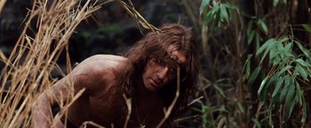 Movie still from “Greystoke: The Legend of Tarzan, Lord of the Apes” (1984), directed by Hugh Hudson – A man with long brown hair is standing in the woods; Close Up shot, Low angle